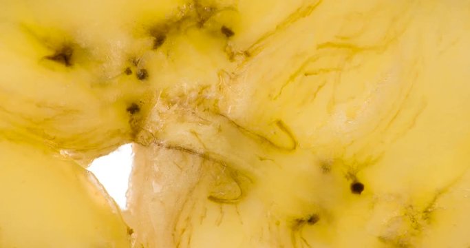 Squeezing a Slice of Ripe Banana. The flesh of the banana is compressed and crushed close-up on a bright white background, creating a juicy splash of pulp and juice. Shooting at 120 fps
