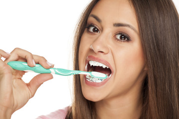 young woman holding a black tooth paste with active charcoal, and black tooth brush on white...