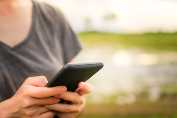 Woman hand using smartphone and laptop with cafe shop sunlight  shade to object beautiful background.