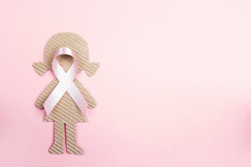 Pink ribbon with girl cardboard doll on pink background for Breast Cancer Awareness symbol.