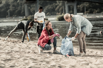 Obraz premium Volunteer with children. Loving responsible mother feeling memorable while volunteering on the beach with her three children