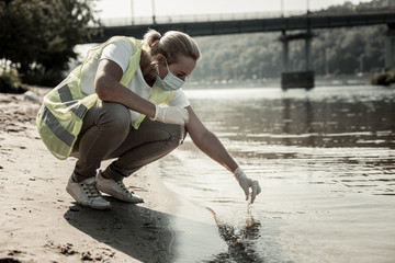 Sanitary inspection. Experienced worker of sanitary inspection service sitting near the river while...