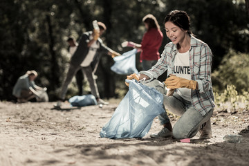 Cleaning forest. Beaming beautiful woman feeling extremely satisfied while cleaning up the forest...