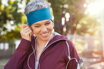 Mature woman adjusting earphones before running