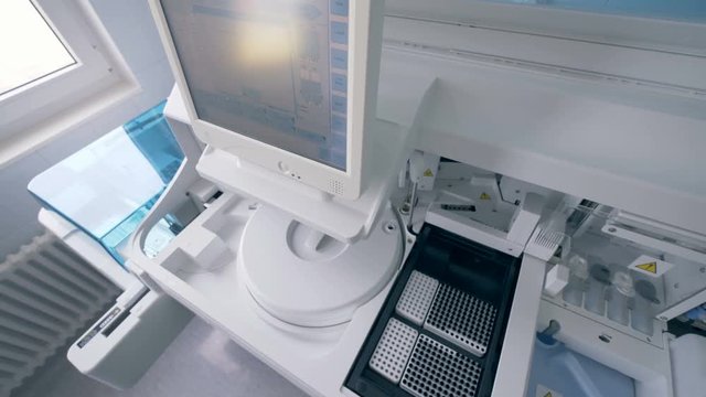 Person works with a machine in a laboratory. A worker types on a monitor of a laboratory machine.