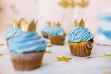 Sweet table with cake and lots of muffins. Bright sweets of blue and white flowers surrounded by gold stars for a birthday, party, jubilee or children's party holiday. 