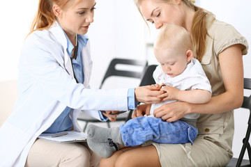 Obraz premium Doctor examining a little boy with stethoscope. Mother holds her son on her lap. Motherless and medicine concept