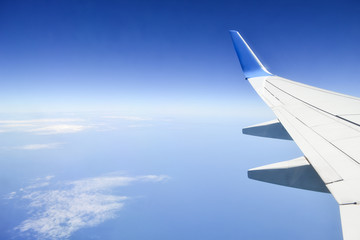 Tranquil view of blue sky with some clouds and sea under the wing of plane. Concept of peaceful. Travel and freedom concept.