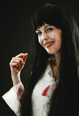 Crazy bloody scary zombie woman smile at camera