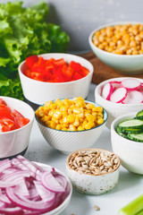 Assortment ingredients for healthy vegetarian salad in different portion bowls on a table. The concept of fitness and vegan food.