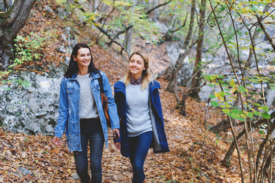 Two young girls friends walking in the autumn forest. Walk in the woods. Girlfriends hiking in the fall.