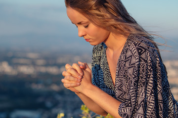 Christian worship and praise. A young woman is praying in the evening.