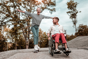 Exciting hobby. Positive young woman standing on the skateboard and looking excited while her...