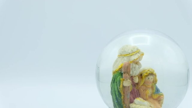 Christmas nativity scene inside glass ball on white background. Left copy space.