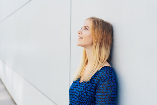 Young smiling woman standing daydreaming
