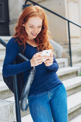 Cute young redhead woman using her mobile