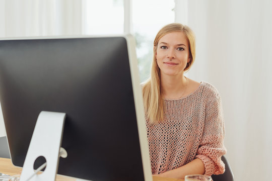 Young blonde woman sitting in front of computer