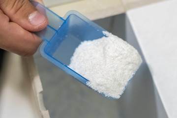 close up female hand pour the washing powder detergent into machine d