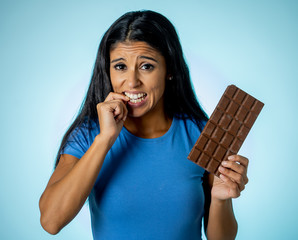 Attractive cute young woman with big bar of chocolate looking at it happy with temptation
