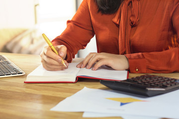 Elegant businesswoman writing down in her work planner. Cropped picture of woman wearing dark...