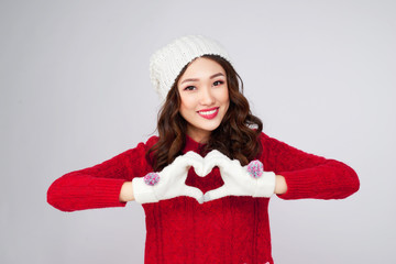 Beautiful smiling woman in warm clothing gesture heart shape