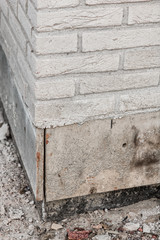 Corner of a white brick wall with part of the basement under construction