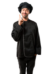 Chef man In black uniform showing and lifting a finger in sign of the best on isolated white background