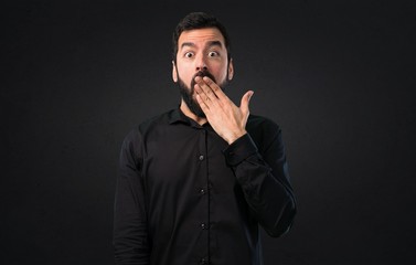 Handsome man with beard making surprise gesture on black background