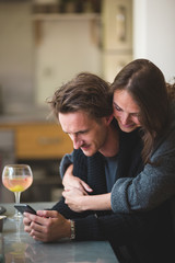 Young couple hugging, looking at the mobile phone
