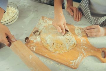 Funny cookies. View of childish hands paying with dough helping her mother with cooking