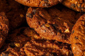Chocolate chip cookies on rustic dark black background. Stacked chocolate chip cookies on brown napkin. Symbolic image with place for text. Freshly baked. Concept for a tasty snack. Sweet dessert. 