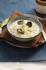 Risotto with black truffle and parmesan cheese in blue plate on rustic linen tablecloth, Copyspace.