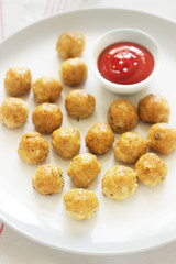 Homemade little chicken meatballs with tomato sauce on a wooden table.