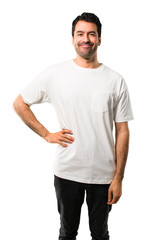 Young man with white shirt posing with arms at hip and smiling on isolated white background