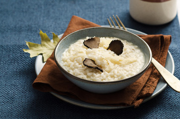 Risotto with black truffle and parmesan cheese in blue plate on rustic linen tablecloth, Copyspace.