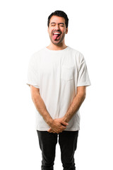 Fototapeta premium Young man with white shirt showing tongue at the camera having funny look on isolated white background