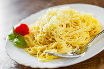 spaghetti pasta with grated cheese in white plate on wooden table