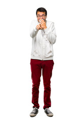 A full-length shot of a Man with glasses and listening music pointing with finger at someone and laughing a lot while covering mouth on white background