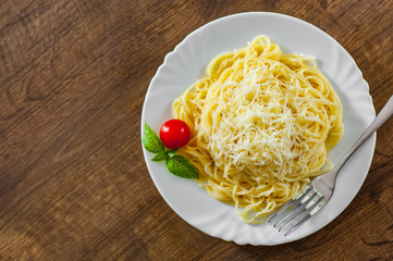 spaghetti pasta with grated cheese in white plate on wooden table
