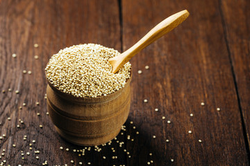 Quinoa, seeds, dry, in a cup on a wooden background, vegan food