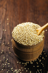 Quinoa, seeds, dry, in a cup on a wooden background, vegan food