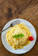spaghetti pasta with grated cheese in white plate on wooden table