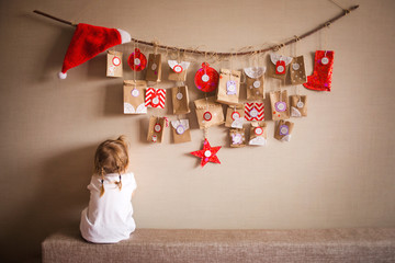 the advent calendar hanging on the wall. small gifts surprises for children. little girl playing...