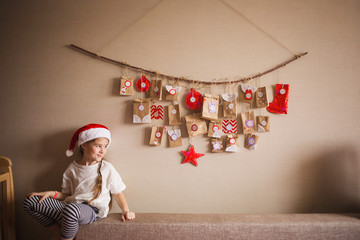 the advent calendar hanging on the wall. small gifts surprises for children. girl looking to the...