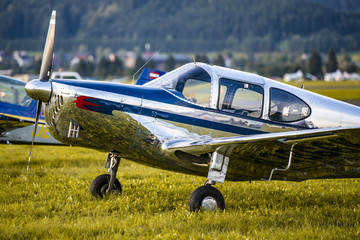 Small airplane in chrome body parked on grass