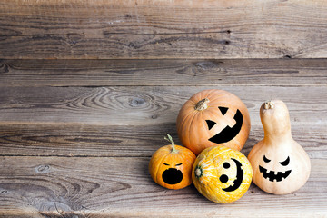 Halloween pumpkins with funny faces on a wooden table. Space for text.