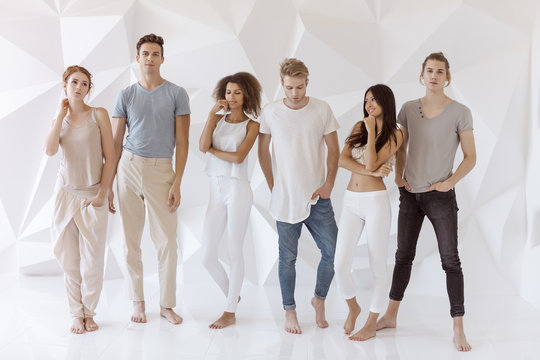 Group of young multi-ethnic beautiful people wearing casual clothes smiling and having fun together against white abstract polygonal background. Asian Caucasian Afro-American attractive stylish men