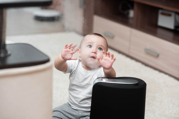 Little baby looks at the humidifier. Moisture in the house concept