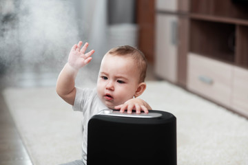 Little baby looks at the humidifier. Moisture in the house concept