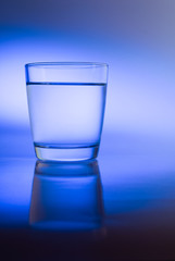 Glass of water in abstract blue